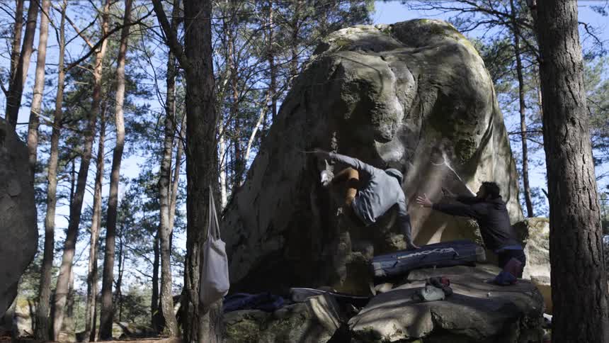 Climber loses his grip and falls from a large rock while another person watches
