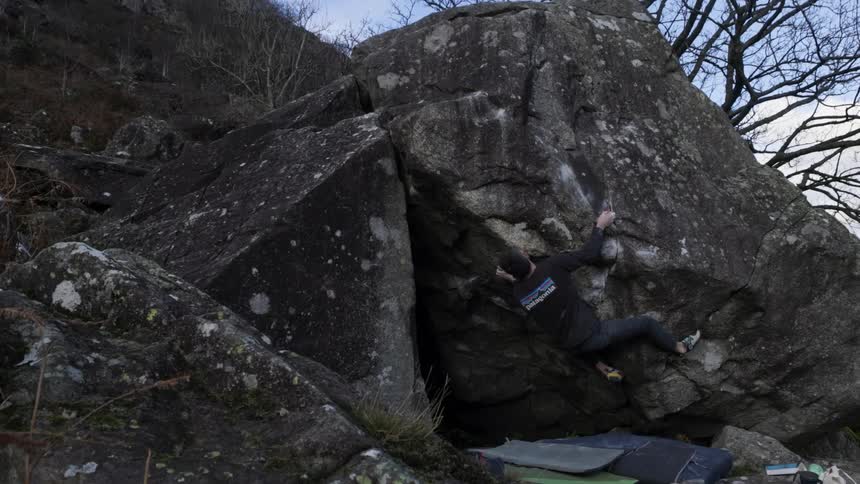 A man climbs a mountain rock at midday