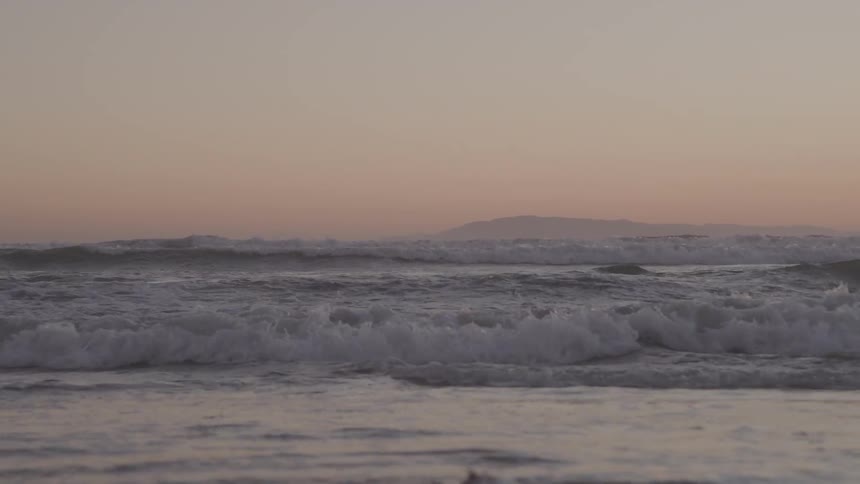 Waves gently break in the sea at sunset