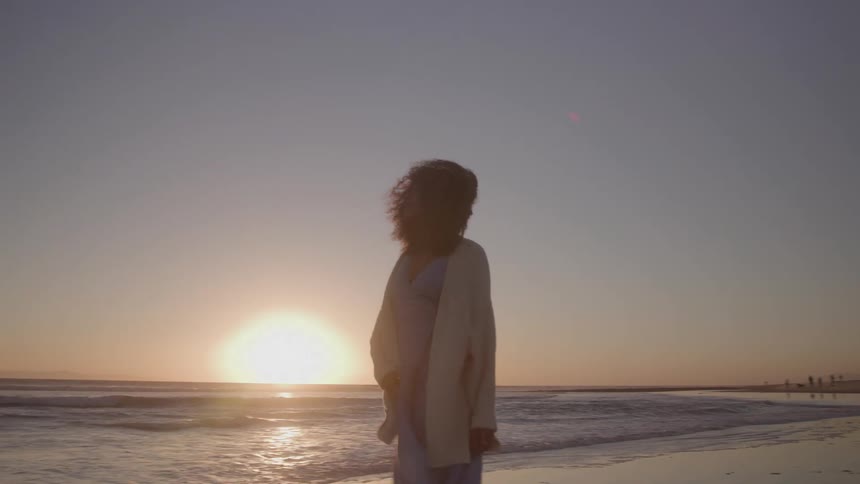 Woman walks on the beach during sunset