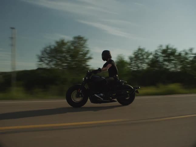 Motorcyclist speeds along an open road on a sunny day