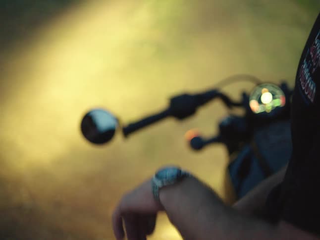 Person looks at the watch on their wrist beside a parked motorcycle