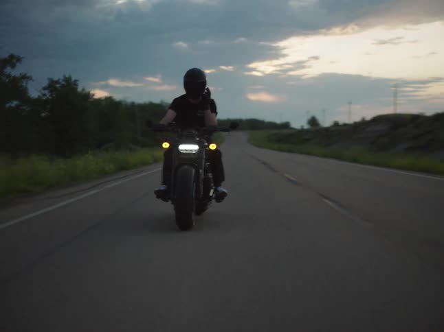 Motorcyclist travels along a rural highway just after dusk