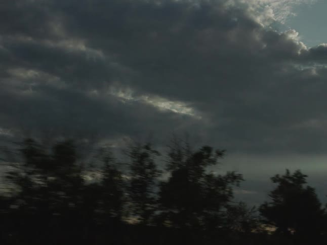 Dense clouds cover part of the sky at dusk over the landscape