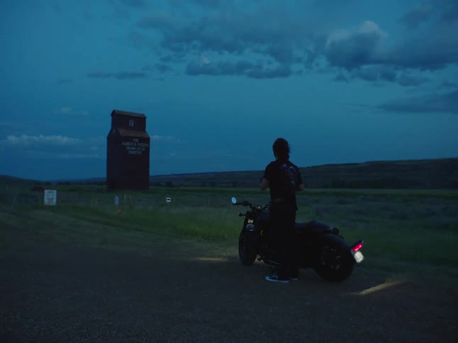 Man stops and gets off motorcycle at dusk