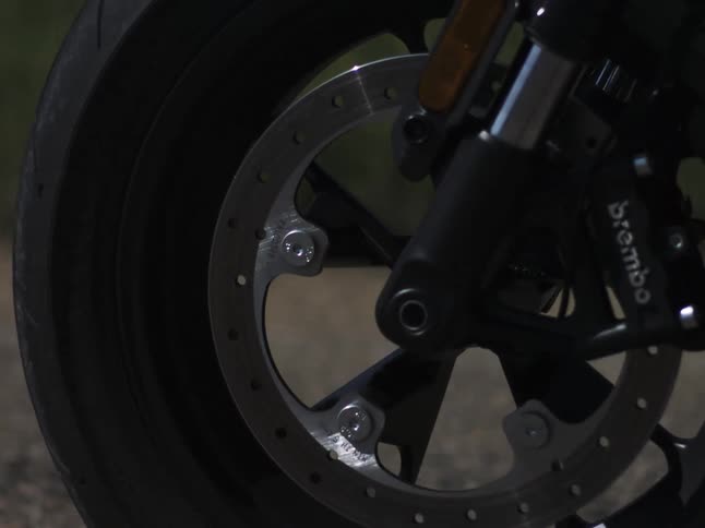 A motorcycles front tire spins as it speeds down the freeway on a sunny day