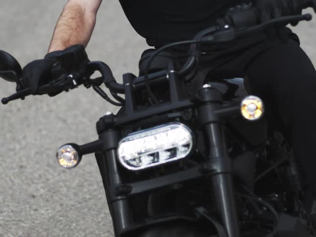 Closeup of the front part of a moving motorcycle with the handlebars being steered