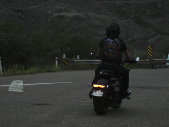 Motorcyclist slows down while approaching a curve at dusk