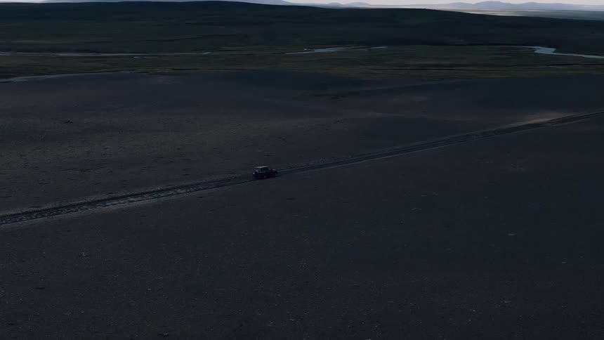A car drives along a countryside highway at sunset