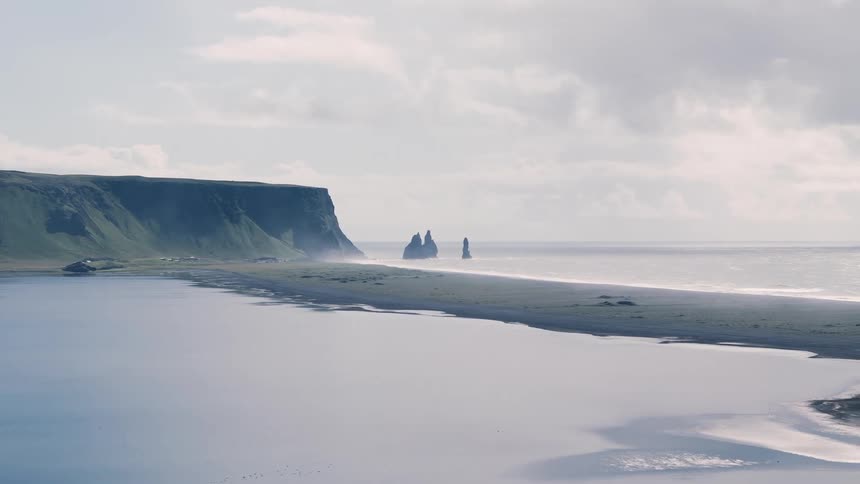 A coastline with a mountain range beneath a cloudy sky