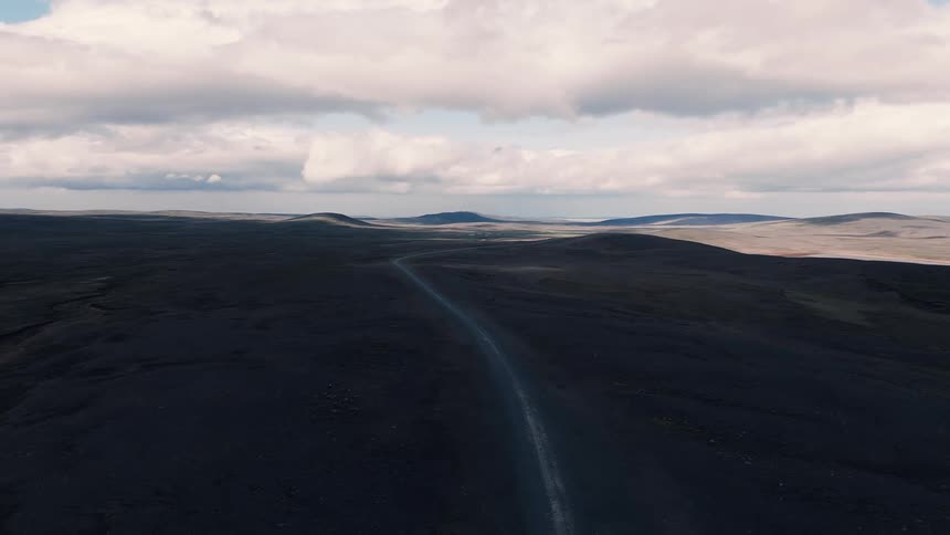 Lonely road crossing an arid landscape under dense clouds
