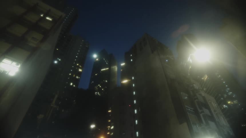 A city view at night with a series of highrise buildings illuminated by glowing lights