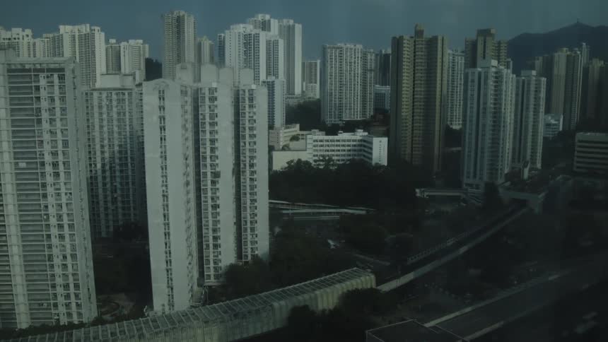 The train passes by the large buildings