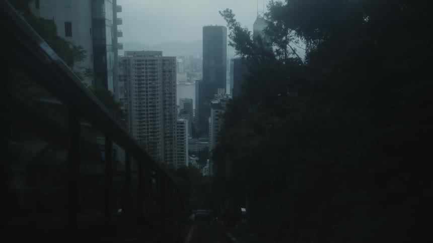 A city skyline at sunrise with a metro line descending downhill toward the city