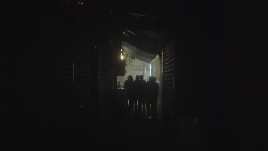 Group of people walks through a dark corridor toward a lit area in the background