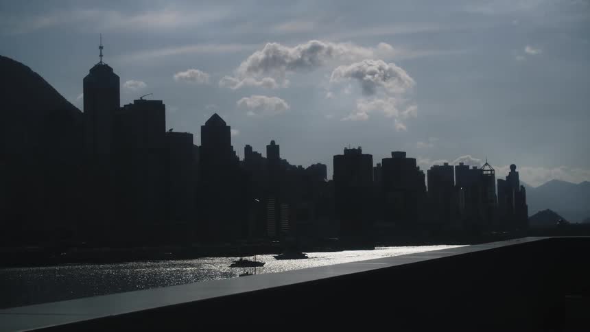 Silhouette of skyscrapers by the water under a partly cloudy sky