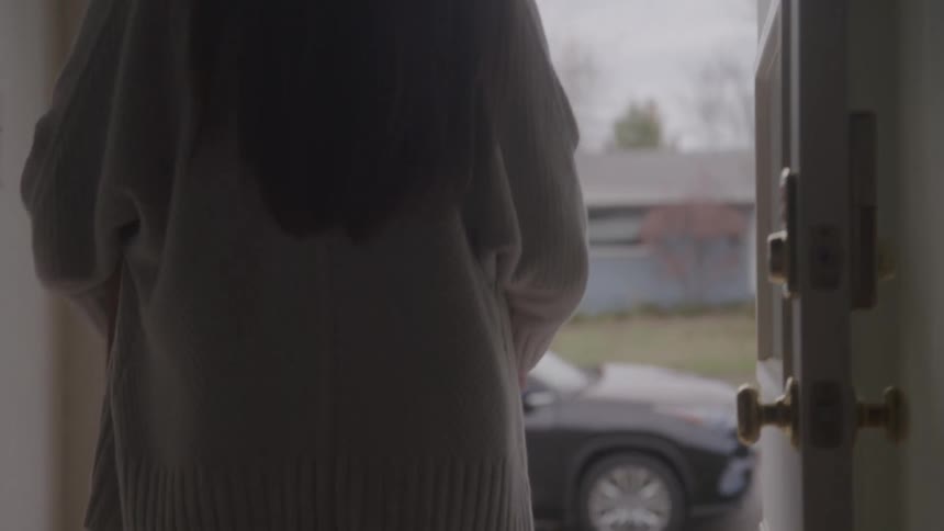 Woman carries a box while moving out of a house that is for sale