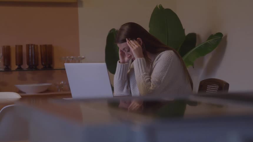 The woman rubs her forehead in front of the laptop