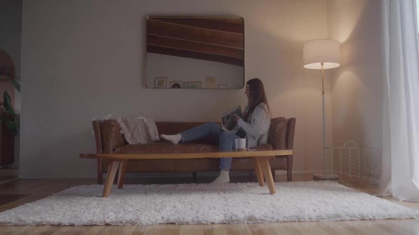 Woman sits on the sofa and opens her laptop
