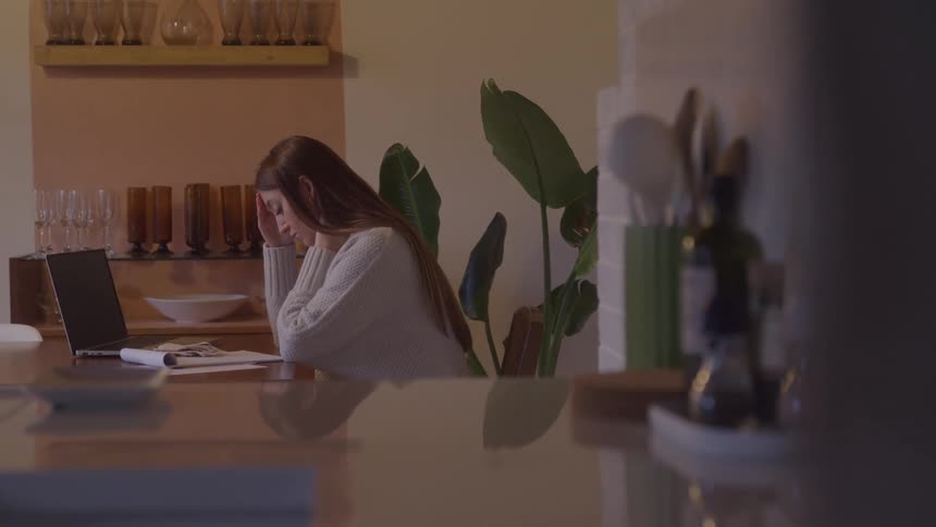 Woman sits at office desk stressed while working