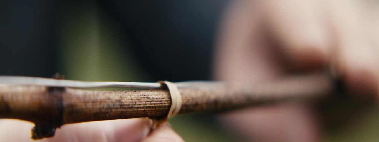 The hunter ties a knot while setting a trap