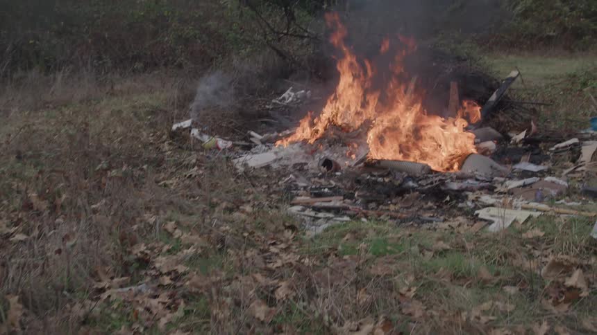 The pile of trash flaring and burning in the grass