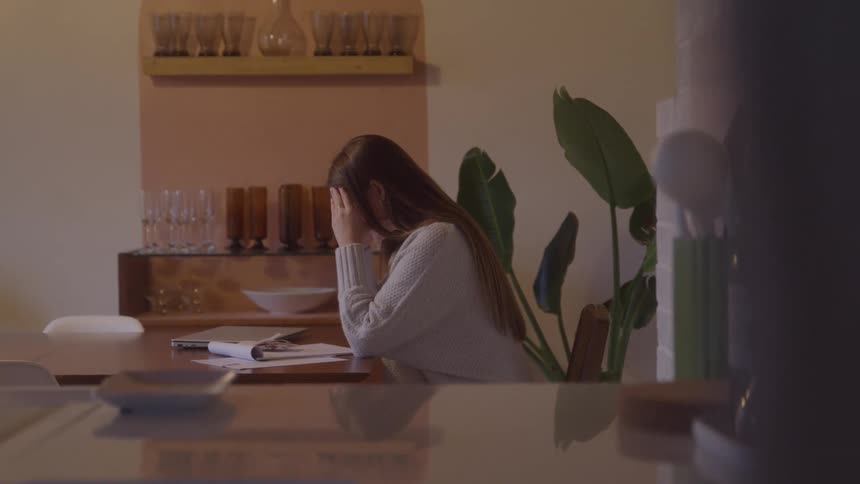 Focused woman works with papers and laptop in a cozy setting with soft lighting