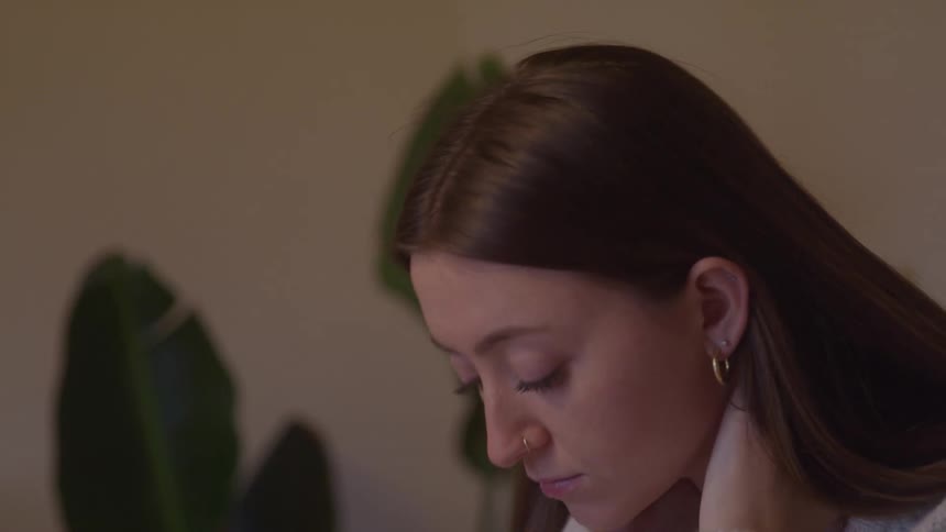 Woman in a light sweater keeps her head down with a dejected expression