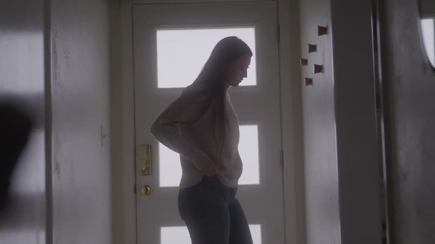The woman nervously paces the hallway