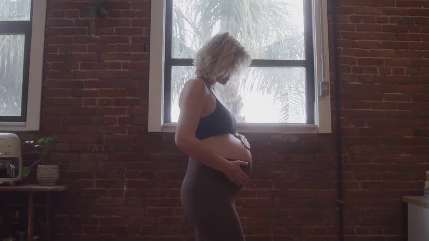 The woman is rubbing her pregnant belly