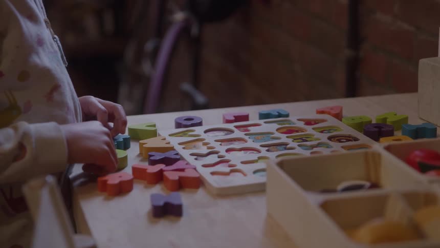 A kid in pajamas plays with toys on a desk indoors