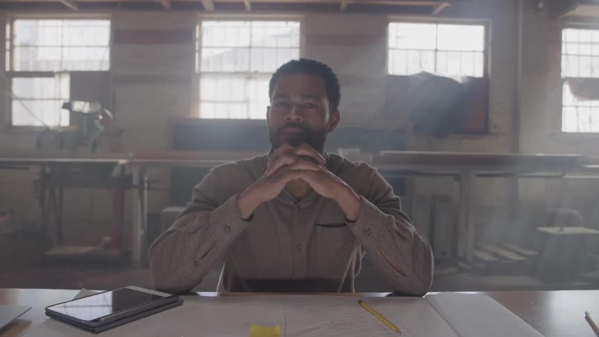 The worker smiles at the desk in the workshop