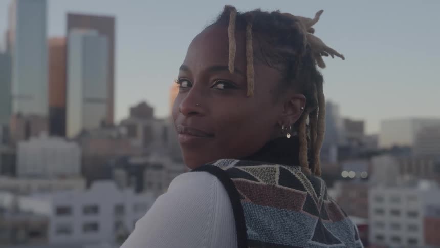 The woman is smiling in front of the city skyline