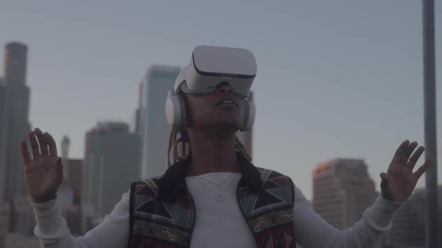 The woman uses a virtual reality headset in front of the skyline
