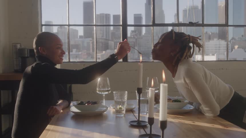 The woman leans over the table and is fed food