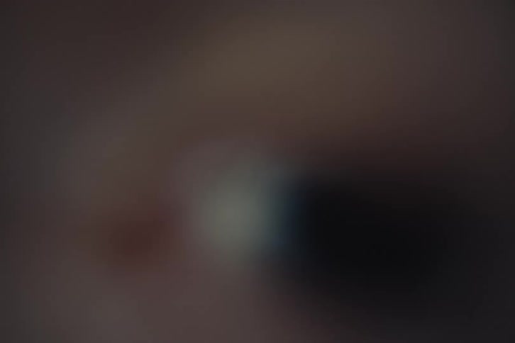 Blurred human eye in closeup appears in a dark setting with soft tones