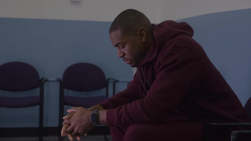 Man sits leaning forward in silent reflection