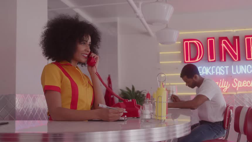 The waitress smiles while answering the phone