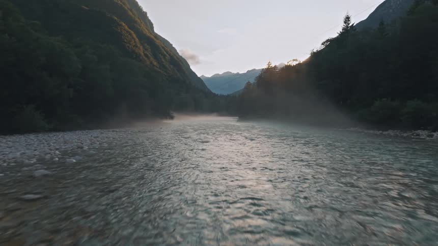 River surrounded by mountains and trees at sunrise