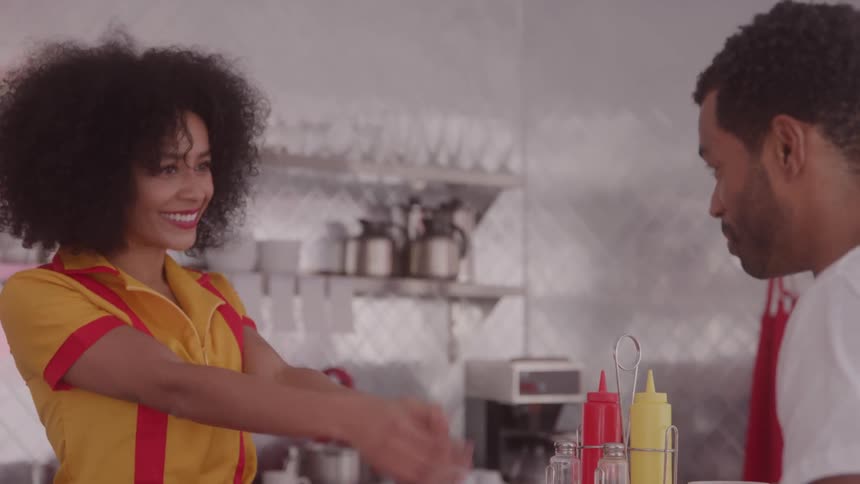 Waitress serves a customer at the counter with a friendly expression