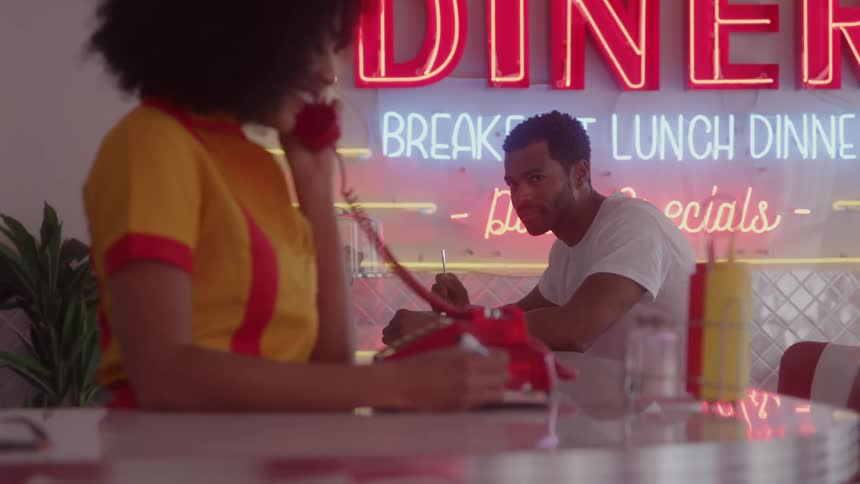 The customer looks over to the waitress on the phone