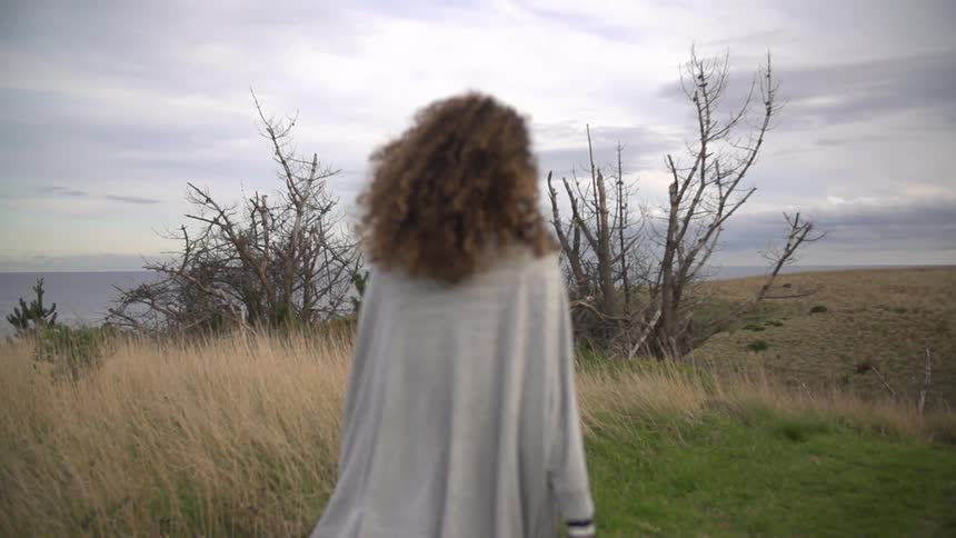 Woman walking on a field on a cloudy day