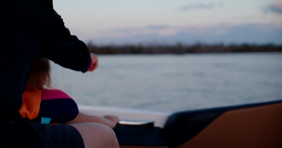 Adult accompanies a child wearing a life jacket as they watch the horizon during a boat ride