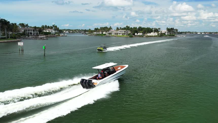 Aerial of boat cruising across harbor with waterfront homes