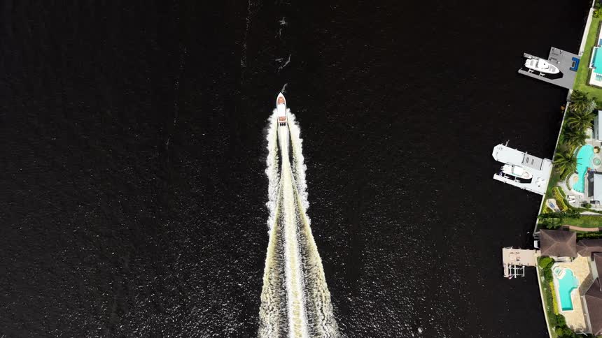 Speedboat at high speed cuts through dark waters leaving a foamy trail