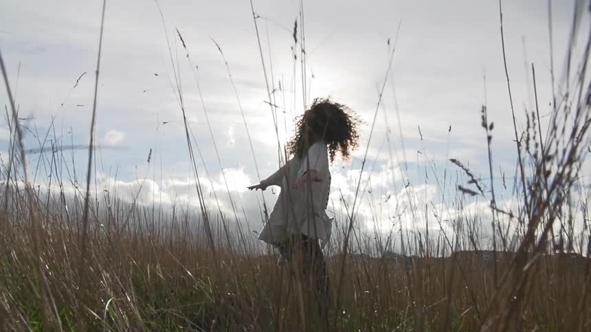 Woman twirling in a grassy field