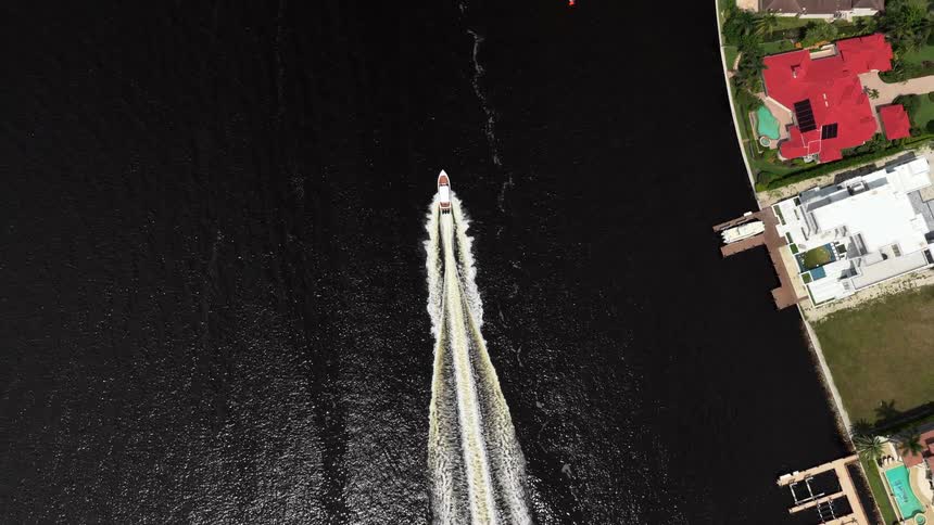 Speedboat moving and leaving white trail in water near residential area