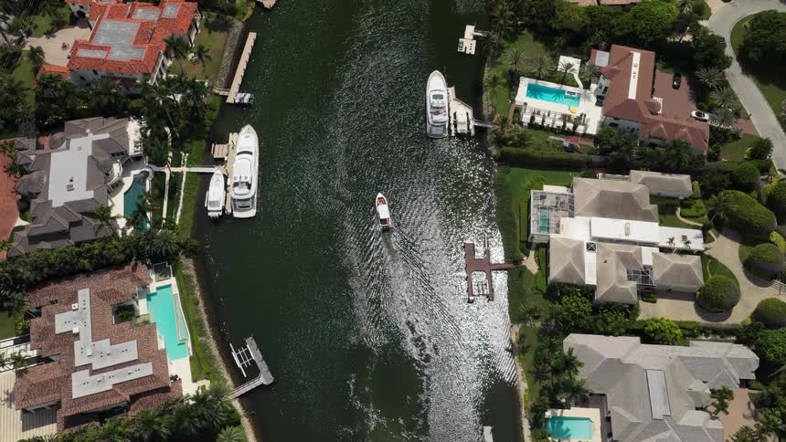 Boat cruising through a residental waterway with waterfront luxury homes