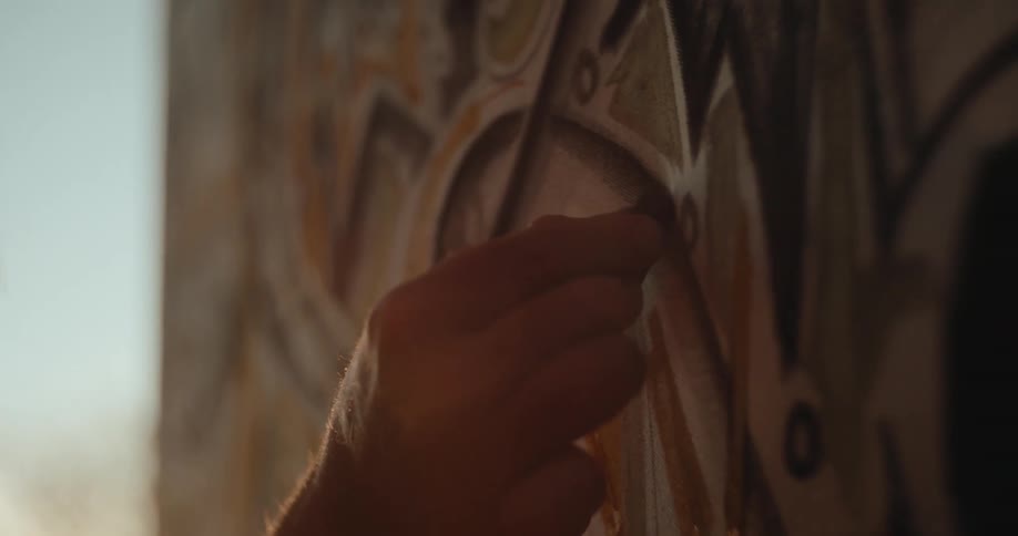 Hand adds earthytoned details to an artwork during the painting process