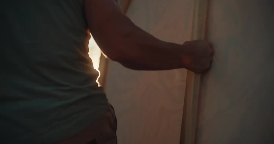 Male arm holds a large wooden frame at sunset